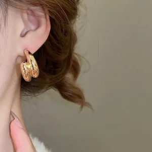 Minimalist double-layered golden C-shaped hoop earrings with a high-shine metallic finish