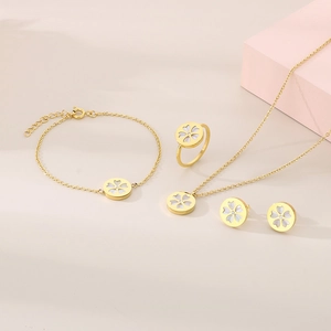 Detailed close-up of gold stainless steel jewelry set with white floral zircon inlay