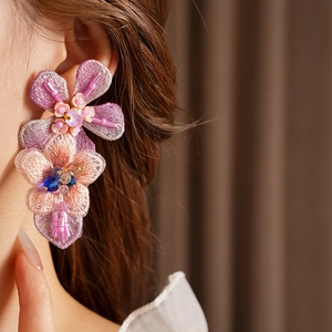 Detailed close-up of embroidered floral earrings with purple and pink beadwork