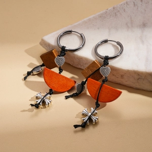 Detail of wooden drop earrings with orange semi-circle and silver heart cross charms