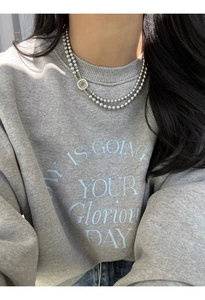 Detail of double-layer grey glass pearl necklace with square shell clasp on a grey sweatshirt