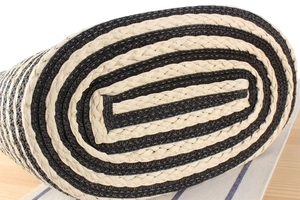 Macro detail showing the thick oval base of a woven beach bag with black and white stripes