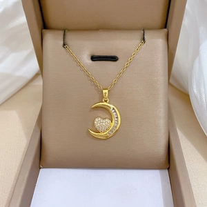 Dettaglio di una collana in acciaio al titanio dorato con ciondolo luna e cuore
