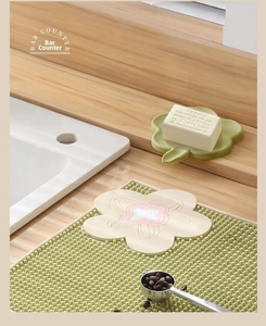 Close-up of green silicone floral soap dish with drainage bumps on a wooden counter