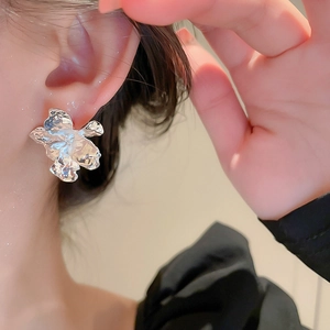 Close-up of stylish silver metallic flower earrings with a unique liquid metal design