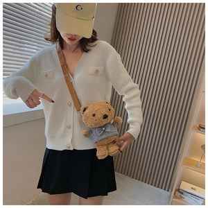 Lifestyle view of brown plush teddy bear crossbody bag worn with white knit cardigan
