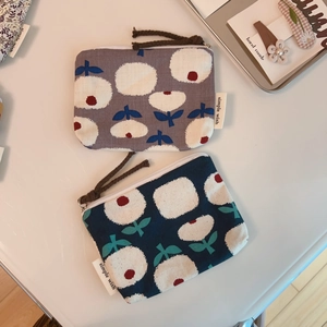 Detail of floral canvas pouches with zipper closures and brown braided pull cords