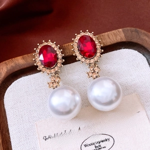 Detailed close-up of vintage oval red stone earrings with diamonds and white pearls