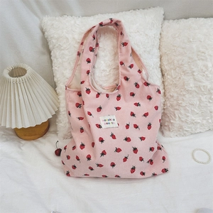 Détail du cabas en velours côtelé rose avec motifs fraises et étiquette en tissu cousue
