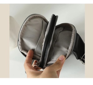Detail view of the black mini chest bag showing dual compartments with herringbone lining
