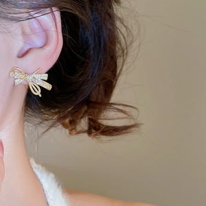 Close-up of gold bow earrings with pavé zircons on model for an elegant look