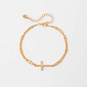 Close-up of gold double-layered bracelet featuring a cross pendant and satellite beads