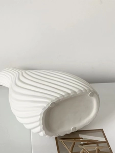 Close-up of white ceramic vase with horizontal wavy textures and anti-slip bottom pads