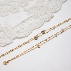 Detail of gold-plated stainless steel double-layer bracelet with sparkling heart charm