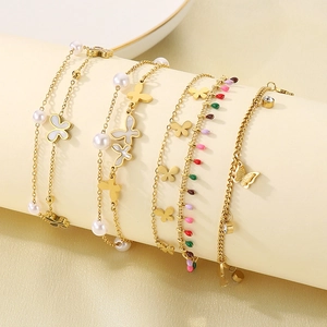 Detailed close-up of layered gold anklets with butterfly charms and pearl accents