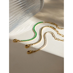 Close-up of 18k gold plated tennis chain bracelet with emerald green and clear zircon