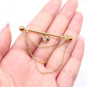 Macro shot of gold nipple piercing ring with triple-layered chains and heart pendant