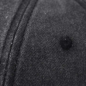 Gros plan sur la double couture et l'œillet brodé de la casquette en coton délavé