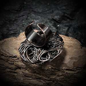 Macro shot of bird nest style bronze wire wrapped adjustable ring on natural bark