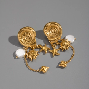 Detailed shot of golden shell earrings with sun, starfish, and pearl tassels on gray background