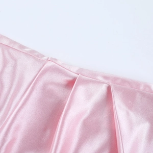 Détail du tissu satiné rose montrant une texture froncée élégante et un fini soyeux
