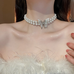 Detail of double-layer pearl necklace featuring a sparkling silver butterfly pendant on neck