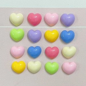 Macro shot of 16 glossy pastel resin hearts arranged in a grid for DIY crafts