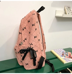 Close-up of pink corduroy backpack with diamond patterns and a large black silk ribbon bow