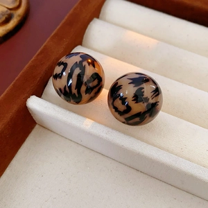 Macro shot of round leopard print stud earrings in brown resin on a jewelry display