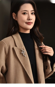 Close-up of a silver snake brooch with sparkling zircons on a camel wool coat lapel
