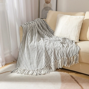 Handmade chunky knit gray and white striped chenille blanket with tassels on sofa