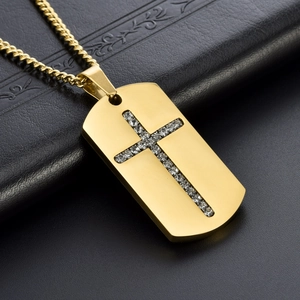 Golden dog tag necklace with a crystal cross pendant on a dark textured background