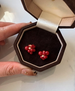 Detail of red cluster earrings with clear crystal in a brown velvet octagon jewelry box