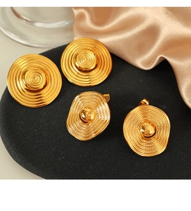 Macro shot of two pairs of vintage gold textured round earrings on a black display pad