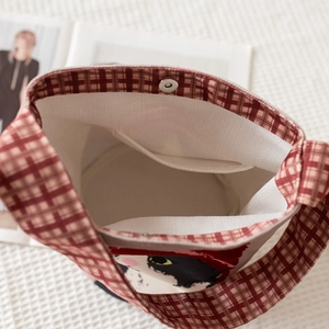 Internal view of bucket bag featuring red plaid straps and magnetic closure snap