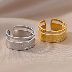Detail of gold and silver layered open rings featuring unique hammered textures on fabric