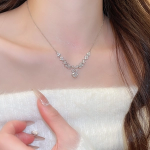 Close-up of elegant V-shaped silver necklace with zircon flower pendant on neck