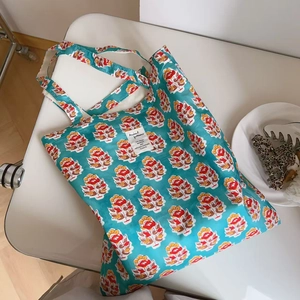 Detail of teal cotton tote bag with retro floral pattern and square label on a chair