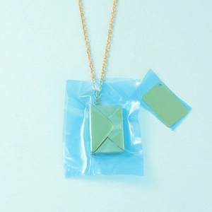 Macro detail of golden envelope pendant with DIY insert card for personalized engraving