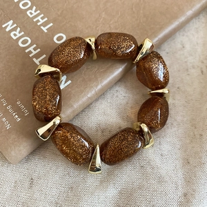 Close-up of amber acrylic oval beads on a bracelet with golden metal spacers