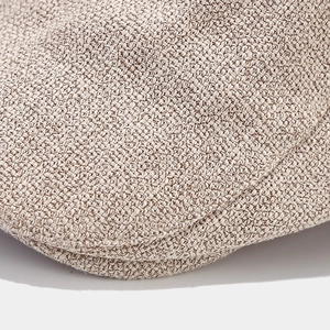 Macro shot of the woven fabric texture and brim details on a vintage beige beret