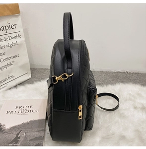 Side view of black quilted faux leather backpack with gold zippers and hardware