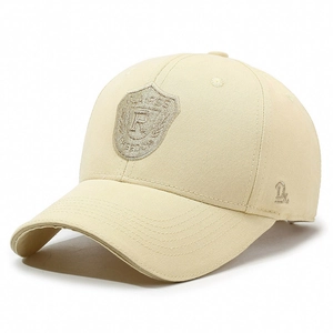 Beige cotton baseball cap featuring classic shield embroidery and side letter detail