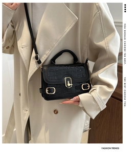 Detail der schwarzen Handtasche mit Krokostruktur, goldenem Verschluss und Tragegurt
