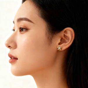 Macro detail of a 18k gold star stud earring with a sparkling central zircon on ear