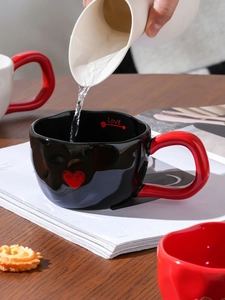 Detail of water pouring into heart pattern ceramic mug with Love text and red handle