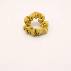Dettaglio di un elastico per capelli in chiffon giallo brillante con pieghe in morbido tessuto