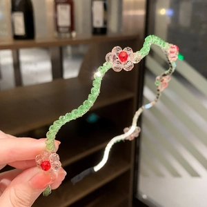 Detail of handmade beaded flower headband set with green pink and red crystals