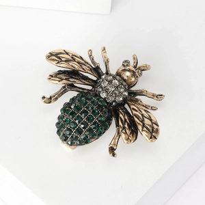 Detail of vintage gold bee brooch with emerald green crystals and clear rhinestones