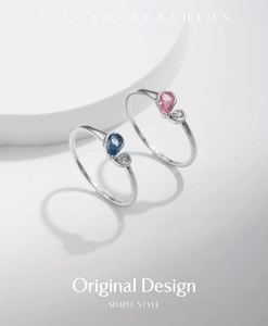 Detailed view of silver rings featuring pear-cut blue and pink gemstones with zircons